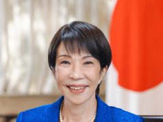 Takaichi Wins Second Term as Japan’s Prime Minister Sanae Takaichi stands at the parliamentary podium smiling while lawmakers applaud her re-appointment as Japan's first female Prime Minister.